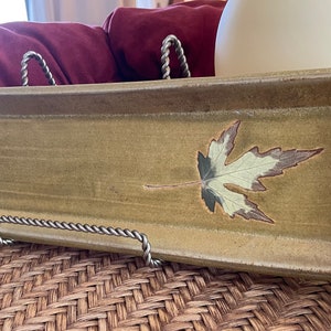 May include: A rectangular ceramic serving tray with a light green glaze and a brown maple leaf design.