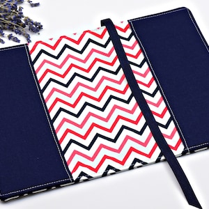 May include: A navy blue book cover with a white, pink, and black chevron pattern. The cover has a black ribbon bookmark.