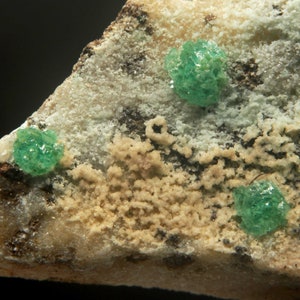 May include: A close-up of a rock with green crystals and white and brown mineral deposits.