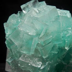 May include: A cluster of green fluorite crystals with a glassy, translucent appearance. The crystals are intergrown and have sharp, well-defined faces.