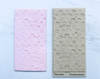 Könnte beinhalten: Eine rosa und beigefarbene Silikonform mit einem sich wiederholenden Muster aus überlappenden Bögen und Kreisen. Die Form ist mit "TTLA-874" und "cooltools" beschriftet.