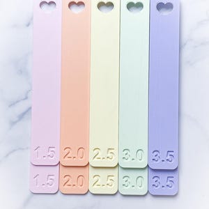 May include: Five pastel-colored plastic rulers with heart-shaped cutouts. The rulers are labeled 1.5, 2.0, 2.5, 3.0, and 3.5.