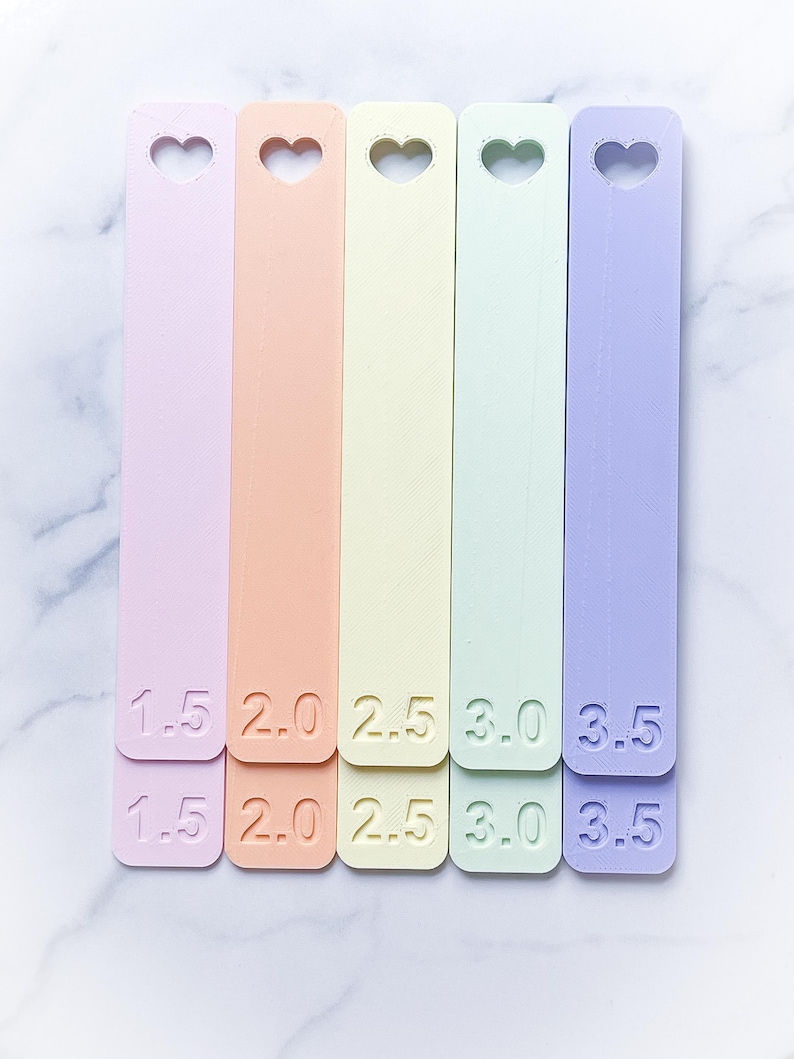 May include: Five pastel-colored plastic rulers with heart-shaped cutouts. The rulers are labeled 1.5, 2.0, 2.5, 3.0, and 3.5.
