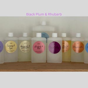 May include: Ten clear glass bottles with labels and different scents. The labels have handwritten text with the names of the scents, including Lavender,  Frankincense & Myrrh,  Honeycrisp & Green Almond,  Rhubarb & Rose,  Black Plum & Rhubarb,  Peach & Nectarine,  Pumpkin Pie,  Big Curl &  Seashell.