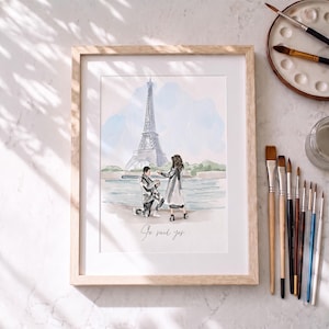 Könnte beinhalten: Ein gerahmtes Aquarellbild, das einen Heiratsantrag vor dem Eiffelturm in Paris zeigt. Das Kunstwerk stellt eine kniende Person vor einer anderen dar, mit dem handschriftlichen Text "Je said yes" darunter. Der Rahmen ist aus hellem Holz.