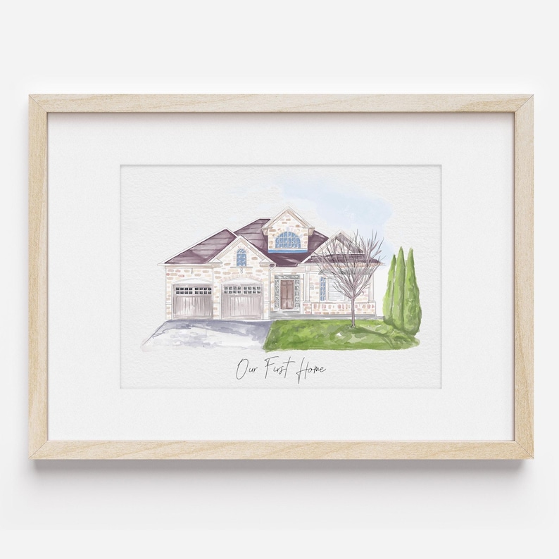 K&ouml;nnte beinhalten: Ein Aquarellbild eines zweist&ouml;ckigen Hauses mit braunem Dach, wei&szlig;en W&auml;nden und einem gr&uuml;nen Rasen. Das Haus hat eine Garage und eine Veranda. Das Bild ist in einem hellen Holzrahmen gerahmt und enth&auml;lt den Text "Our First Home".