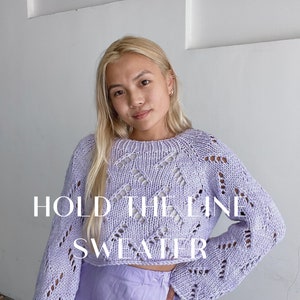 May include: A light purple crochet sweater with a lacy pattern. The sweater is cropped and has long sleeves. The text "HOLD THE LINE SWEATER" is superimposed on the image.