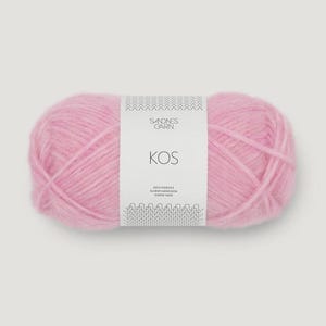 May include: A skein of soft, light pink yarn. The yarn is labeled "KOS" by Sandnes Garn. The label is white with black text and a decorative border. The yarn appears fluffy and is tightly wound.