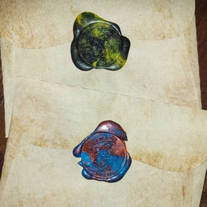 May include: Two wax seals with the Hogwarts crest. The top seal is green and yellow, the bottom seal is blue and red.