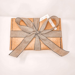 May include: A brown cardboard box with a brown and black ribbon tied in a bow. The box is wrapped in a brown paper with a black border.