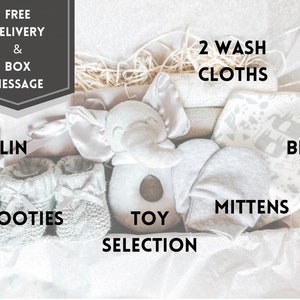 Puede incluir: Una caja de regalo para beb&eacute; gris y blanca con un juguete de elefante gris, botines grises, guantes grises, un babero gris y dos toallitas. La caja tambi&eacute;n incluye una manta de muselina gris y un juguete gris.