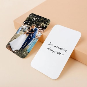 Puede incluir: Dos tarjetas fotográficas rectangulares. Una tarjeta presenta una foto de boda de una pareja besándose, con invitados al fondo. La otra tarjeta es blanca con el texto "Our memories, always close" en cursiva negra.