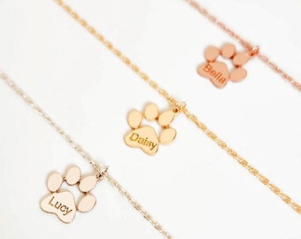 May include: Three gold necklaces with paw print charms. The charms are engraved with the names "Lucy", "Daisy", and "Bella".