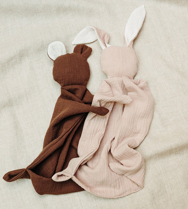 K&ouml;nnte beinhalten: Zwei weiche Pl&uuml;schtiere in Form eines B&auml;ren und eines Hasen. Der B&auml;r ist braun und der Hase ist rosa. Beide Spielzeuge haben wei&szlig;e Ohren und sind aus einem weichen, strukturierten Stoff gefertigt.