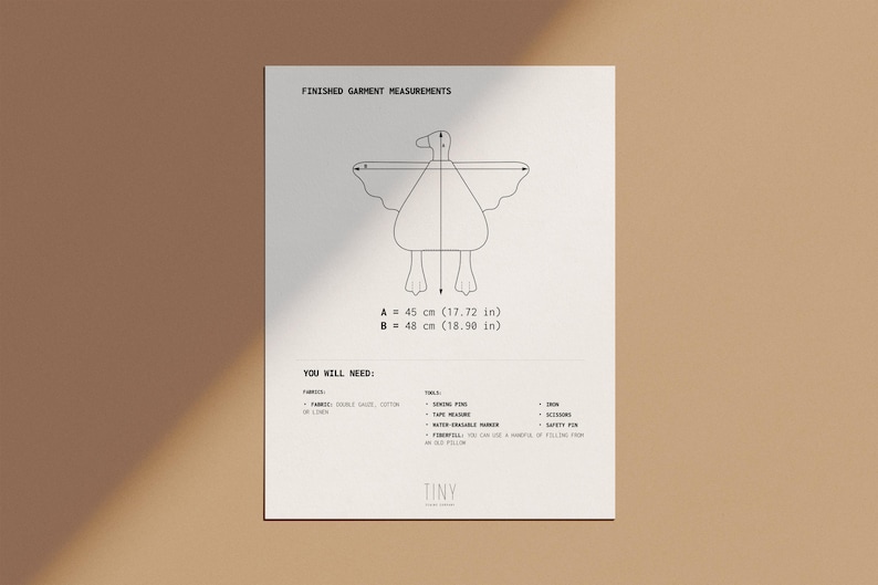 May include: A white paper with a line drawing of a bird-like figure, with measurements of 45 cm (17.72 in) and 48 cm (18.90 in). The text "FINISHED GARMENT MEASUREMENTS" and "YOU WILL NEED" are also present.