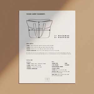 May include: A black and white line drawing of a tote bag with measurements in inches and centimeters. The drawing shows the finished garment measurements for the bag, including the height and width. The text "FINISHED GARMENT MEASUREMENTS" is at the top of the page. The text "TINY" is at the bottom of the page.