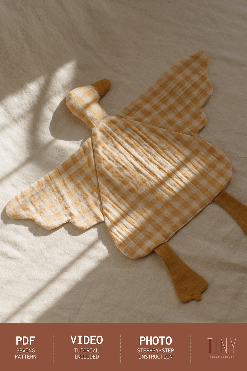 May include: A handmade goose-shaped plush toy in a yellow and white gingham pattern. The toy has a long neck, wings, and legs made of a soft fabric. The image also includes text that says "PDF Sewing Pattern", "Video Tutorial Included", and "Photo Step-by-Step Instruction".