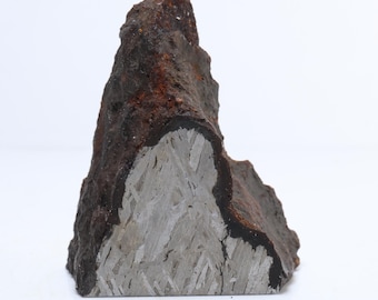 May include: A rough, irregularly shaped rock with a dark, rusty brown exterior and a gray, crystalline interior. The rock has a layered appearance, with a visible transition between the outer and inner sections. The object is set against a white background.