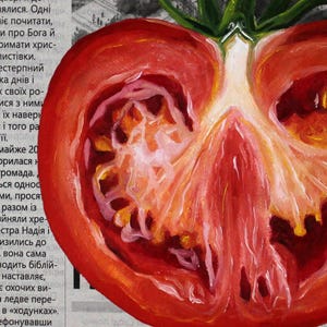 May include: A close-up of a red tomato cut in half, showing the inside with seeds and a white core. The tomato is on a newspaper background.