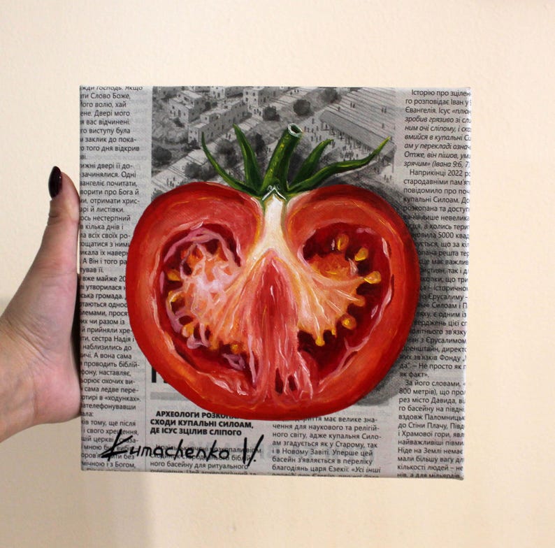 May include: A painting of a red tomato cut in half, with the seeds and flesh visible. The tomato is painted on a newspaper background with text in Russian.
