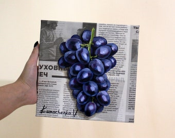 May include: A square canvas painting featuring a cluster of dark purple grapes with green stems, layered over a background of black and white printed newspaper text in Russian. The artist's signature, Kumachenko, is visible in the bottom left corner.
