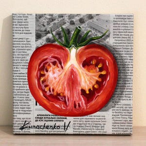 May include: A painting of a red tomato cut in half, showing the inside of the tomato. The painting is on a canvas with a newspaper background. The text on the newspaper is in Russian.