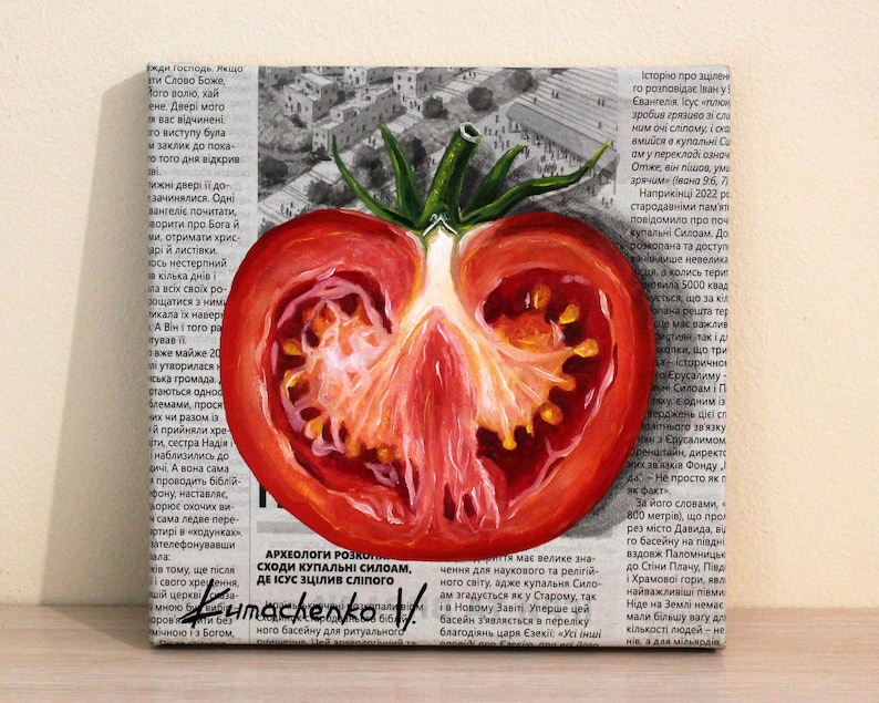May include: A painting of a red tomato cut in half, showing the inside of the tomato. The painting is on a canvas with a newspaper background. The text on the newspaper is in Russian.