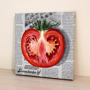 May include: A painting of a red tomato cut in half, revealing the inside of the tomato. The painting is on a canvas with a newspaper background. The text on the newspaper is in Russian. The painting is signed "Kumachenko V."