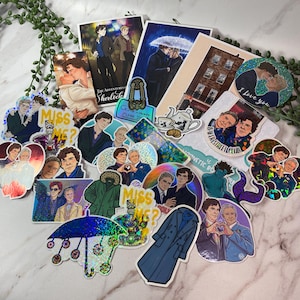 Könnte beinhalten: Eine Sammlung von Aufklebern und Drucken mit Illustrationen von Charakteren aus einer Fernsehserie. Die Aufkleber haben holografische und Glitzereffekte, mit Text wie "I love you" und "Miss me?". Die Drucke zeigen Szenen und Charaktere.