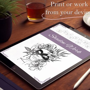May include: A digital art print displayed on a tablet, featuring a black and white illustration of a face with a mask and floral elements. The text "Shadow Work" is visible. The image is on a wooden surface.