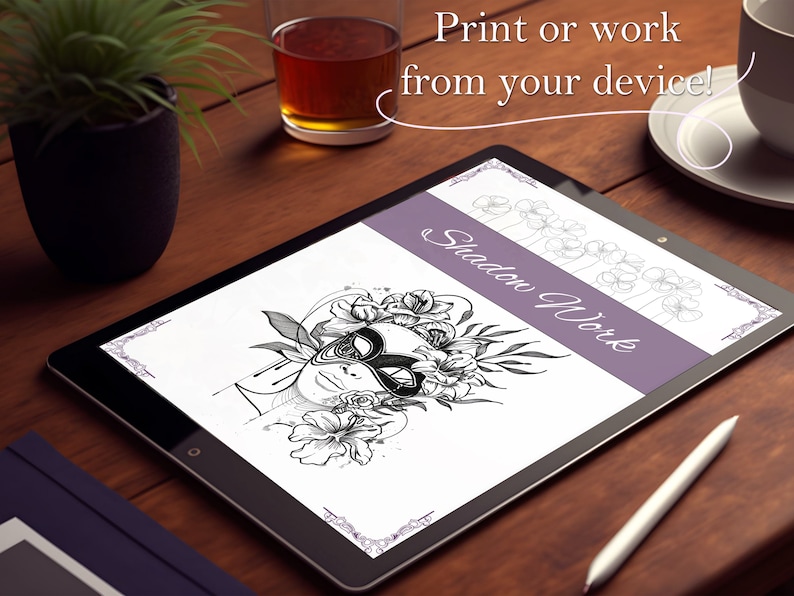 May include: A digital art print displayed on a tablet, featuring a black and white illustration of a face with a mask and floral elements. The text "Shadow Work" is visible. The image is on a wooden surface.