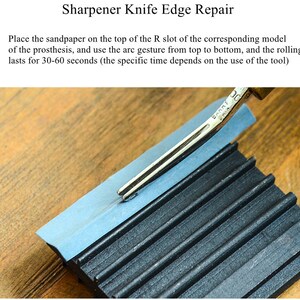 May include: A close-up of a knife sharpener with a metal blade resting on a blue piece of sandpaper. The sharpener has a black rubber base with ridges. The text "BARRI" is visible on the blade.