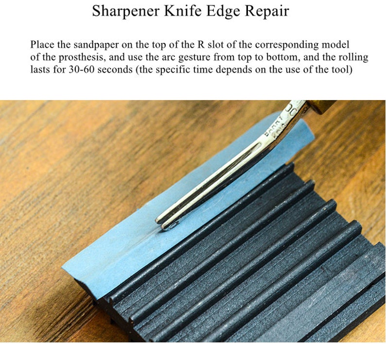 May include: A close-up of a knife sharpener with a metal blade resting on a blue piece of sandpaper. The sharpener has a black rubber base with ridges. The text "BARRI" is visible on the blade.