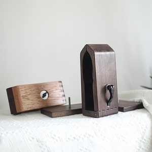 Puede incluir: Un soporte de madera con una tapa con bisagras y una peque&ntilde;a manija de metal. El soporte est&aacute; dise&ntilde;ado para sostener auriculares.