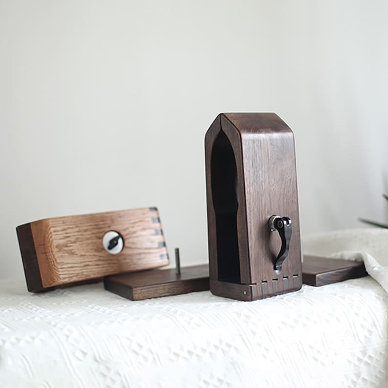 Puede incluir: Un soporte de madera con una tapa con bisagras y una peque&ntilde;a manija de metal. El soporte est&aacute; dise&ntilde;ado para sostener auriculares.