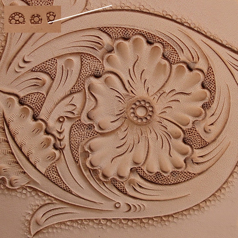 Op de afbeelding: Close-up van een lederen handwerkproject met een bloemmotief. Het ontwerp heeft een grote bloem met een kleinere bloem in het midden. Het leer is lichtbruin van kleur en heeft een getextureerd oppervlak.