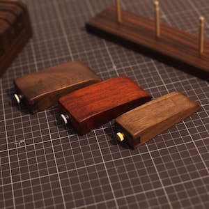 May include: Three wooden blocks with brass accents. The blocks are different sizes and colors, including brown, red, and a darker brown.