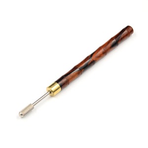 May include: A wooden tool with a brown and black striped handle and a metal tip. The tool is used for crafting and has a brass accent.
