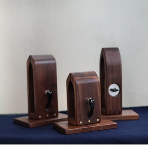 Puede incluir: Tres soportes de madera con un dise&ntilde;o &uacute;nico, cada uno con una peque&ntilde;a manija negra. Los soportes est&aacute;n hechos de madera marr&oacute;n oscura y tienen un dise&ntilde;o simple y elegante.