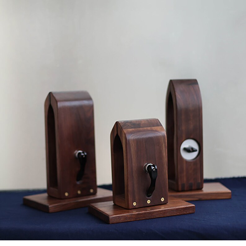 Puede incluir: Tres soportes de madera con un dise&ntilde;o &uacute;nico, cada uno con una peque&ntilde;a manija negra. Los soportes est&aacute;n hechos de madera marr&oacute;n oscura y tienen un dise&ntilde;o simple y elegante.