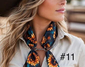 May include: A dark-colored scarf featuring a vibrant sunflower pattern in shades of orange and yellow, secured at the neck with a silver-toned metal bit-style clasp. The scarf is worn over a light beige button-down shirt. The text #11 is visible.