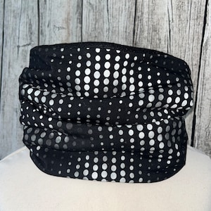 Può includere: Passamontagna nero e bianco con un motivo a pois. I pois sono bianchi su uno sfondo nero.