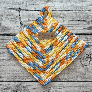 Op de afbeelding: Een gehaakte ovenwant in tinten blauw, geel, oranje en wit met een bruin label met de tekst "Handmade with Love".