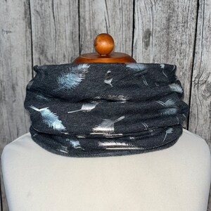 May include: A gray neck warmer with a silver feather print.