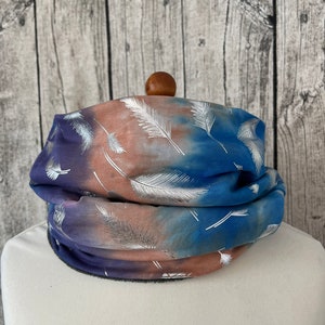 Könnte beinhalten: Ein blauer und brauner Halsschmuck mit einem silbernen Federdruck. Der Halsschmuck ist aus einem weichen, dehnbaren Stoff gefertigt und perfekt, um sich im Winter warm zu halten.