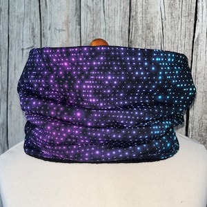 Może przedstawiać: Czarny komin z powtarzającym się wzorem małych, opalizujących kropek w odcieniach fioletu, błękitu i różu.