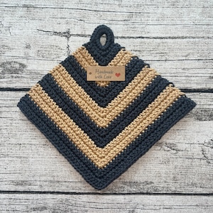 Peut inclure: Un dessous de plat crocheté noir et beige avec une étiquette brune indiquant "Handmade with Love" et un cœur rouge.