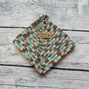 May include: A crocheted pot holder in brown, white, and blue with a brown tag that says "Handmade with Love" and a red heart.
