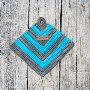 Könnte beinhalten: Grauer und türkisfarbener gehäkelter Topflappen mit einem braunen Etikett, auf dem "Handmade with Love" und ein rotes Herz stehen.