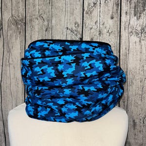 Peut inclure: Un tour de cou en camouflage bleu et noir. Le tour de cou est fait d'un tissu doux et extensible et est conçu pour vous garder au chaud par temps froid.